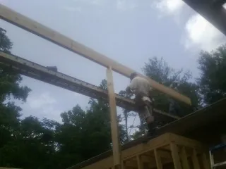 Carpenter setting a ridge beam over a new addition frame — Ice Dam Removal by Roofing Brothers in Barksdale