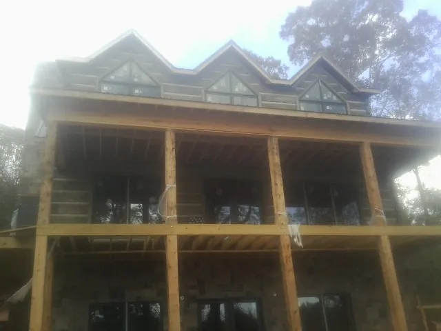 Dormers and porch framing on a large log home under construction — Roof Coating work by our crew in Barksdale