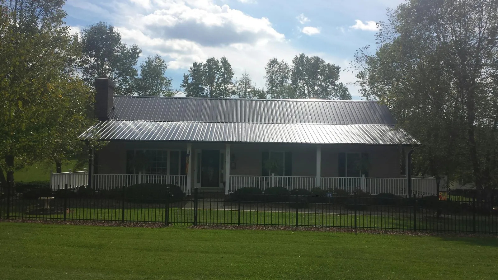 Gray metal roof on a brick ranch with a full width front porch — Gutter Guard Installation work by our crew in Barksdale