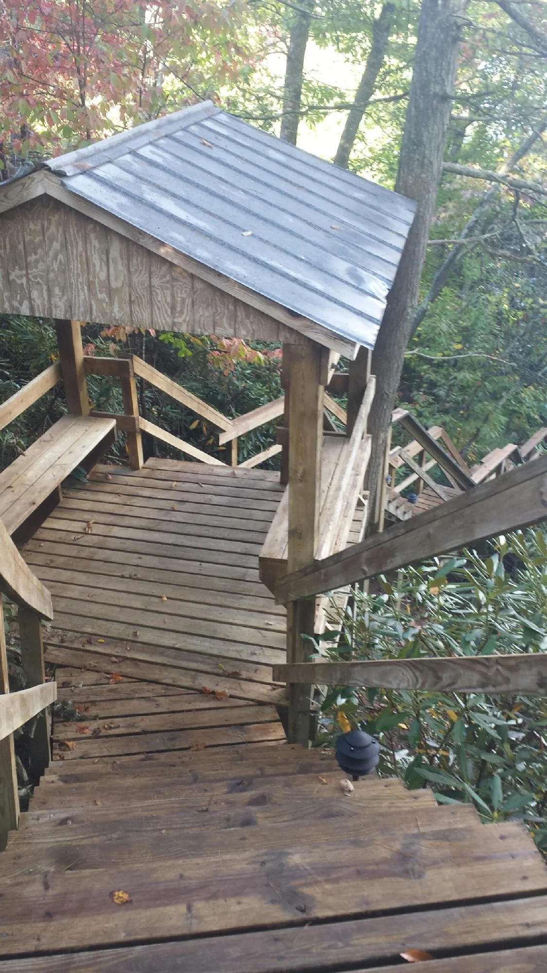 Metal roofed shelter over wooden steps on a wooded walkway — Skylight Repair & Installation work by our crew in Barksdale