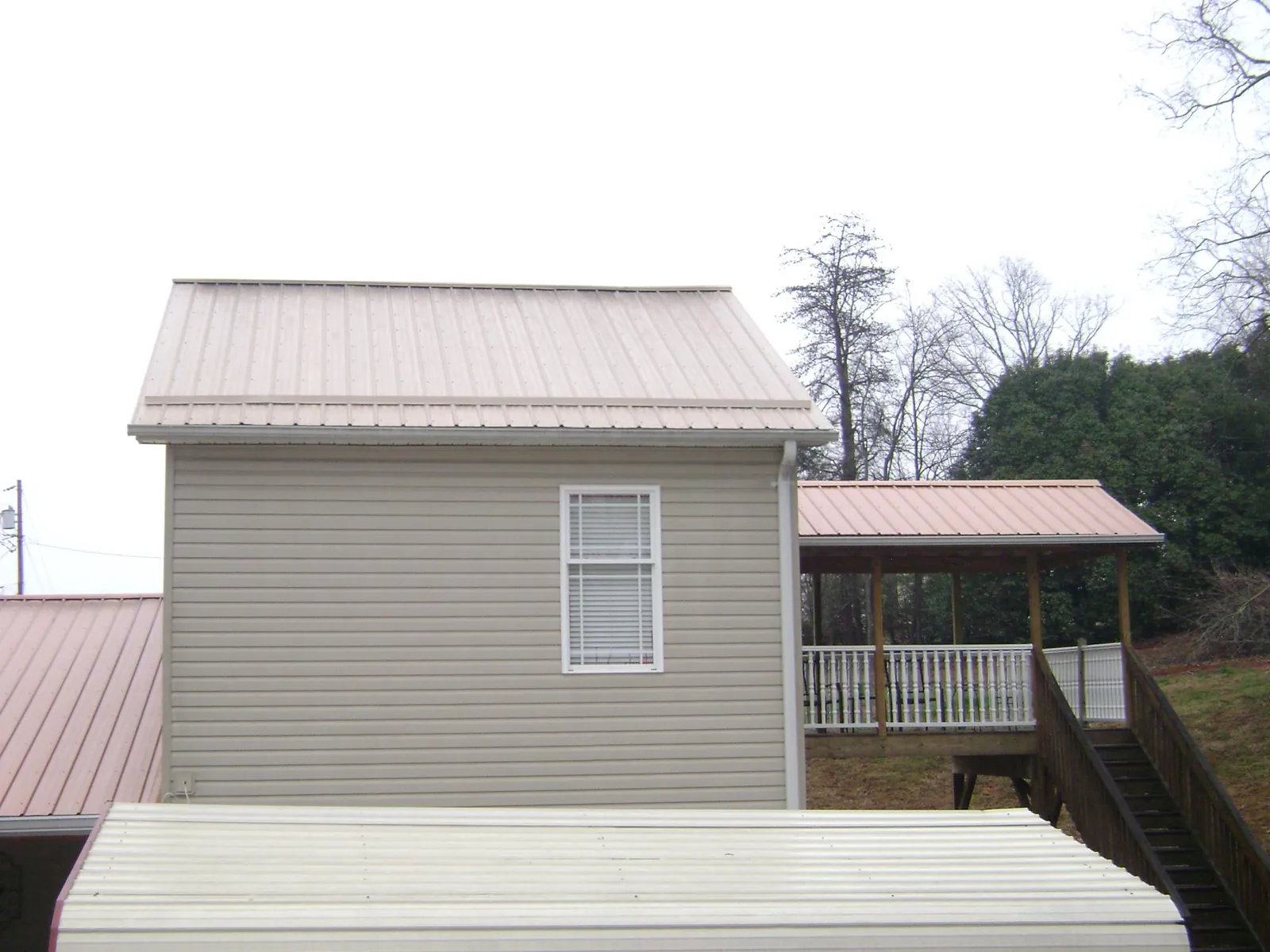 Tan metal roofs on a two story addition and attached porch, from a Roof Replacement job in Barksdale