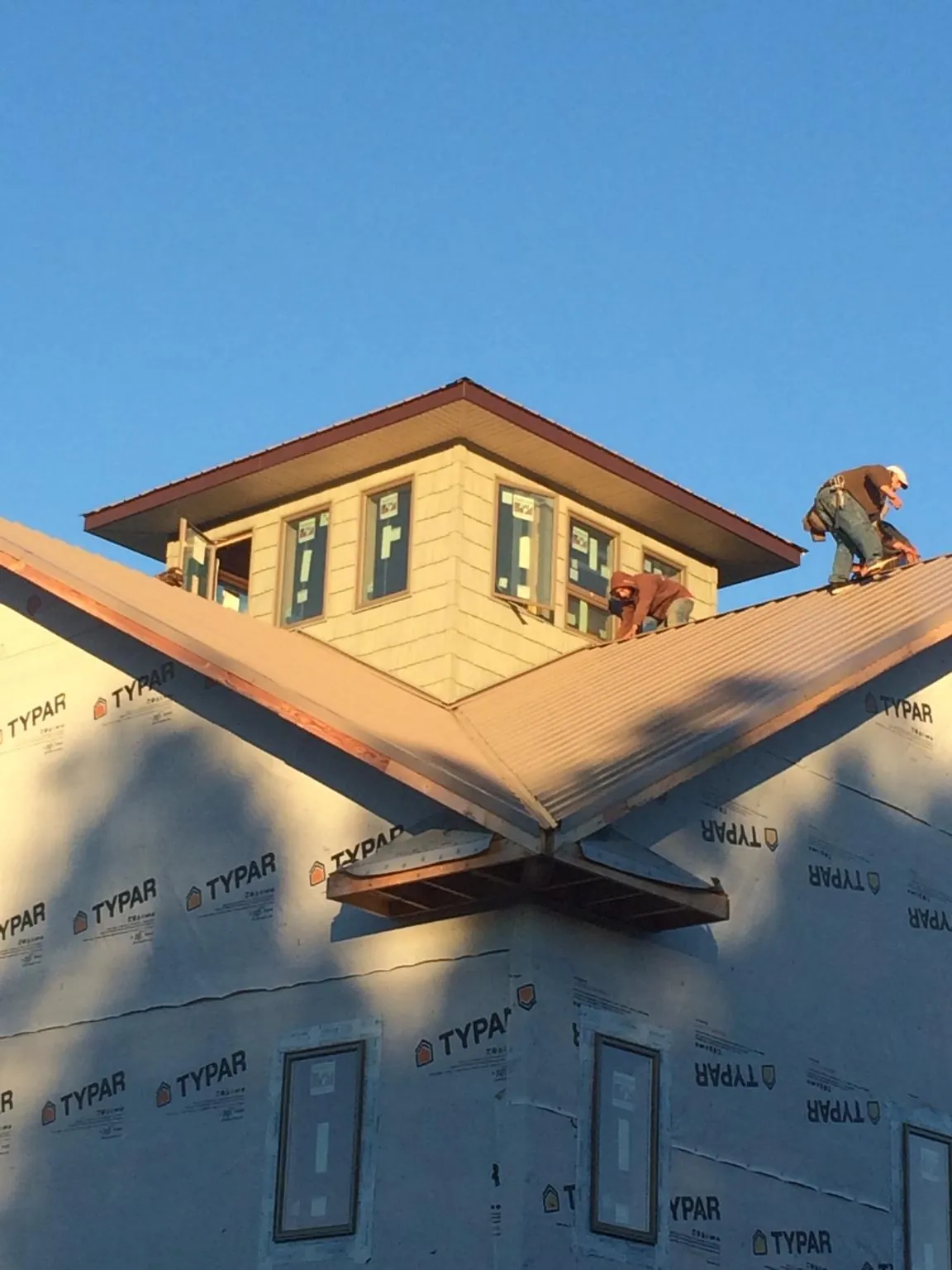 Roofers working around a rooftop cupola on a new metal roof at sunset — Roof Waterproofing in Barksdale by Roofing Brothers